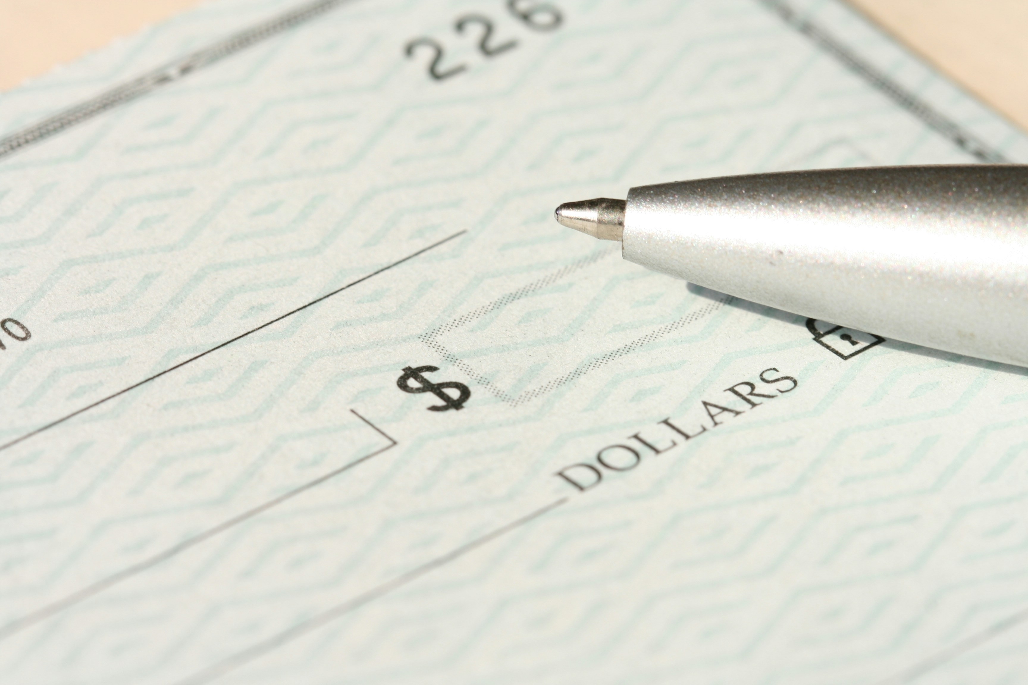A pen sitting on top of a blank bank check.